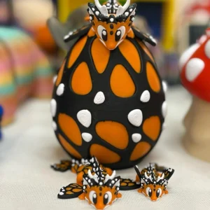 3D printed monarch butterfly dragon set in pink and black featuring three articulated dragons (Daddy, Momma, and Baby) with butterfly wings and a matching decorative dragon egg.